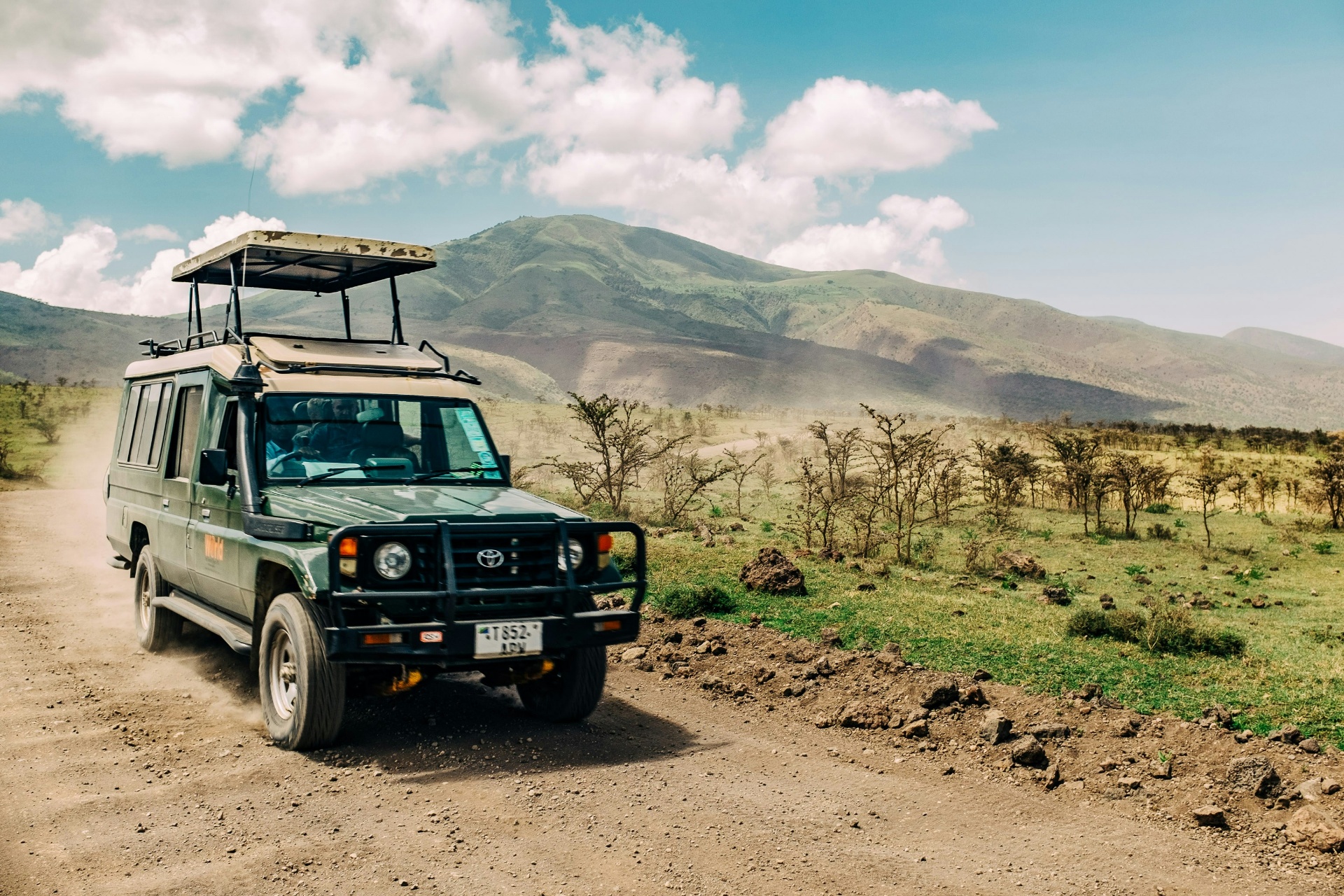 Safari jeep on a dirt road with mountains